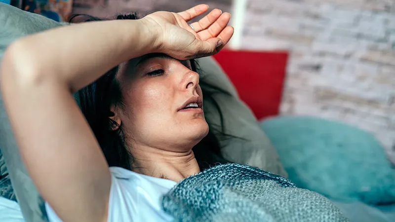 A woman lying in bed feeling exhausted, illustrating fatigue as a common symptom of leukemia