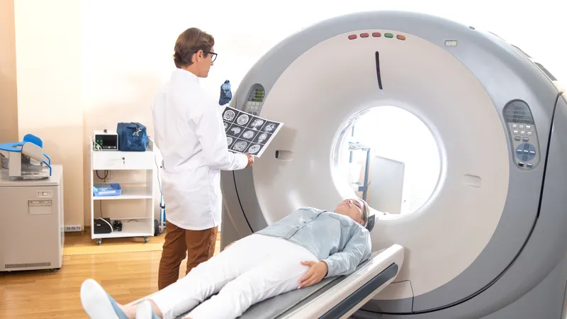 Patient undergoing a head CT scan with doctor reviewing brain images