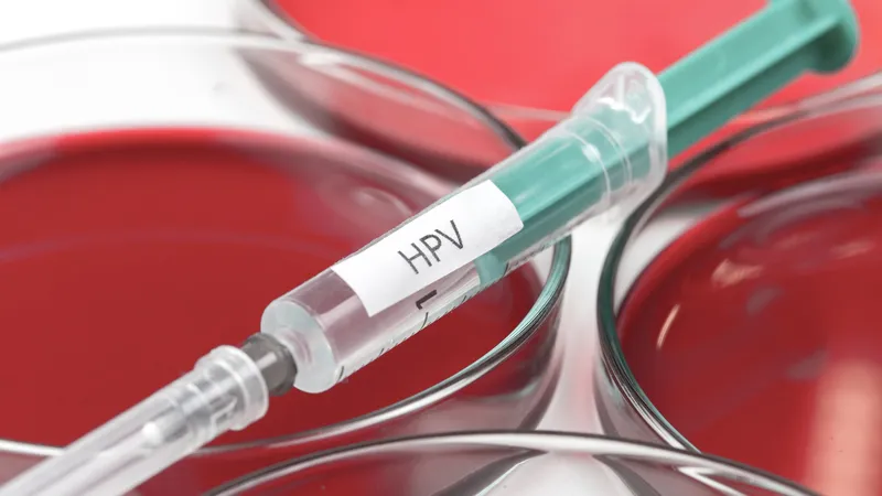 Close-up of a syringe labeled HPV placed over petri dishes, representing HPV testing for cervical cancer diagnosis