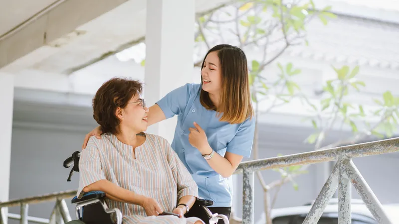 Healthcare worker supporting a patient in a wheelchair during recovery