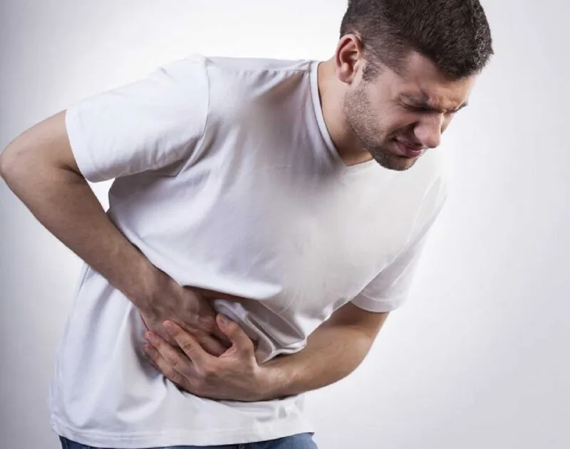 Man holding his stomach in pain after eating, a possible symptom of advanced gastric cancer