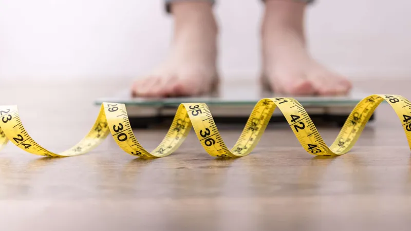 Unexplained weight loss shown with a person standing on a scale and a measuring tape, a possible symptom of lymphoma