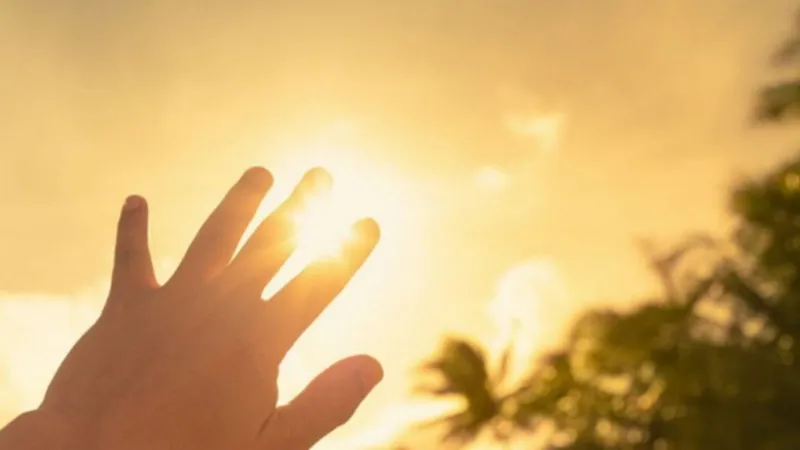 Squamous Cell Carcinoma Hand reaching toward bright sunlight, symbolizing ultraviolet (UV) exposure from the sun, a risk factor for squamous cell carcinoma.