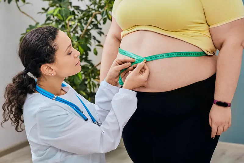 Doctor measuring abdominal circumference to assess obesity and health risks