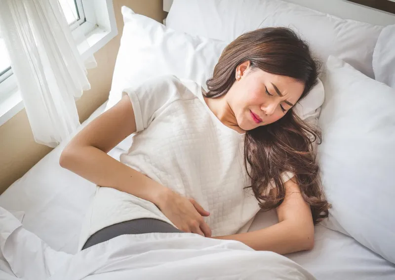 Woman experiencing lower abdominal pain, a common symptom of endometrial cancer