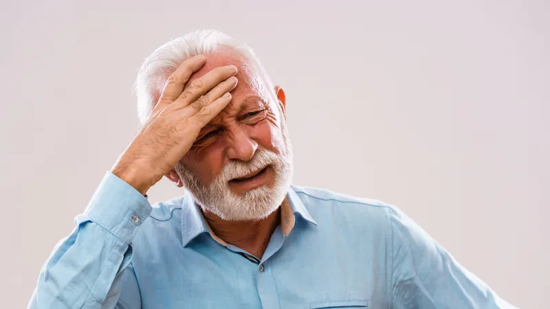 Elderly man suffering from headache due to high blood pressure
