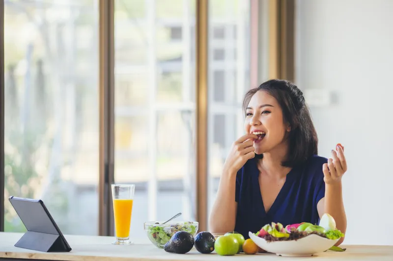 A woman eating a healthy meal with fruits and vegetables to reduce the progression of endometrial cancer