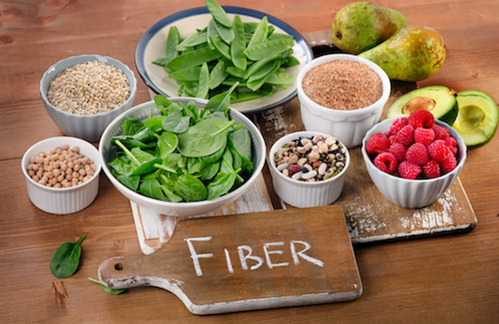 Assorted high-fiber foods including spinach, beans, grains, and fruits for a healthy diet