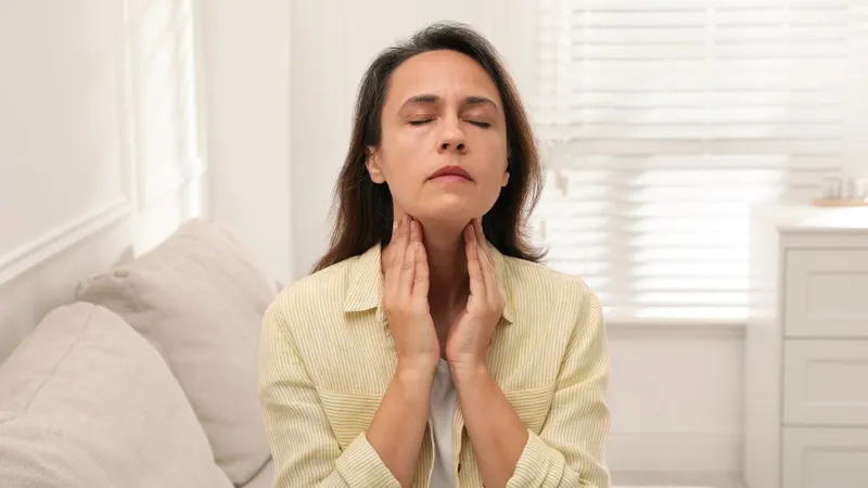 Woman checking neck swelling, a possible symptom of Non-Hodgkin Lymphoma