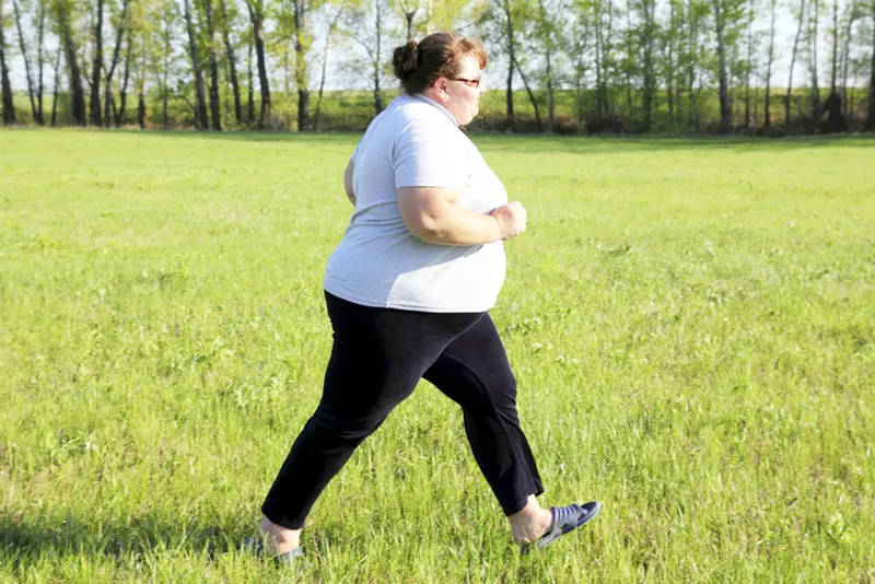 Person with obesity doing moderate physical activity through brisk walking outdoors