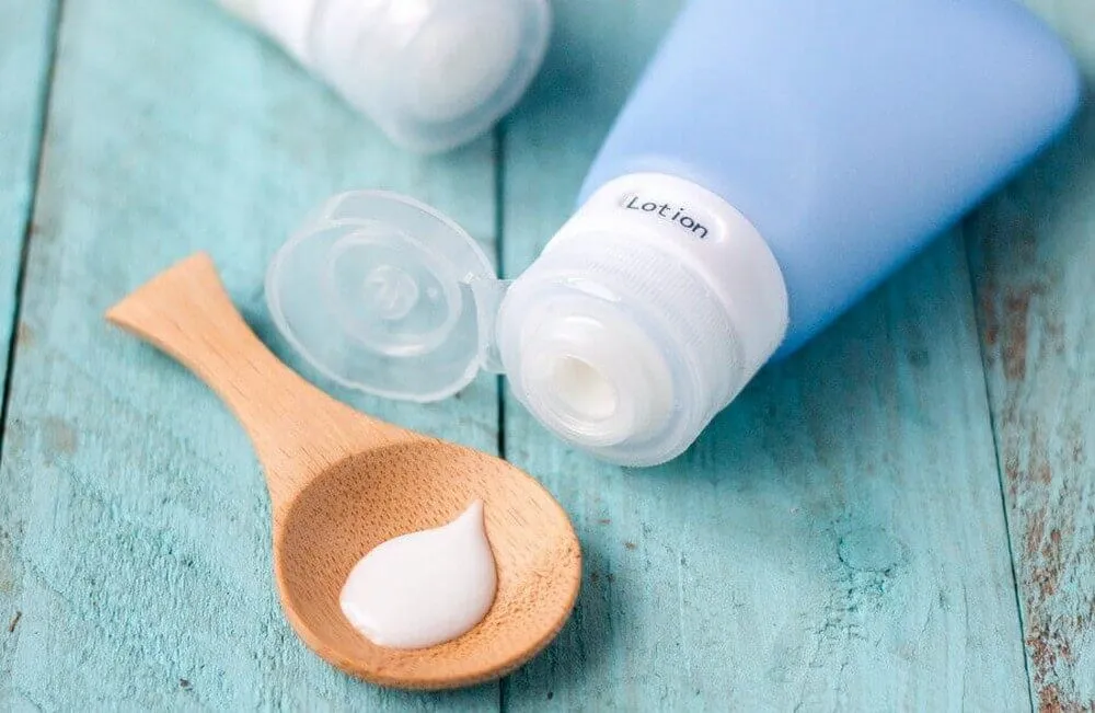Skincare lotion on a wooden spoon, illustrating products that may contain alcohol or harsh chemicals irritating the skin