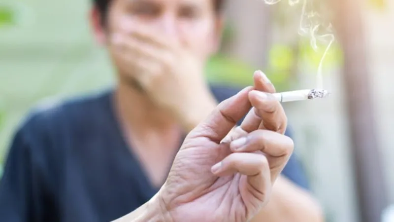 Close-up of a person holding a cigarette, highlighting smoking as the leading cause of lung cancer