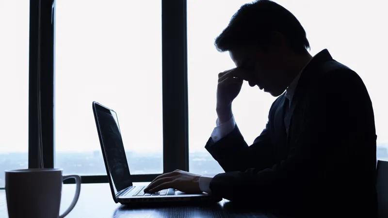 Man feeling dizzy and stressed at work due to a sudden drop in blood pressure, indicating hypotension risk