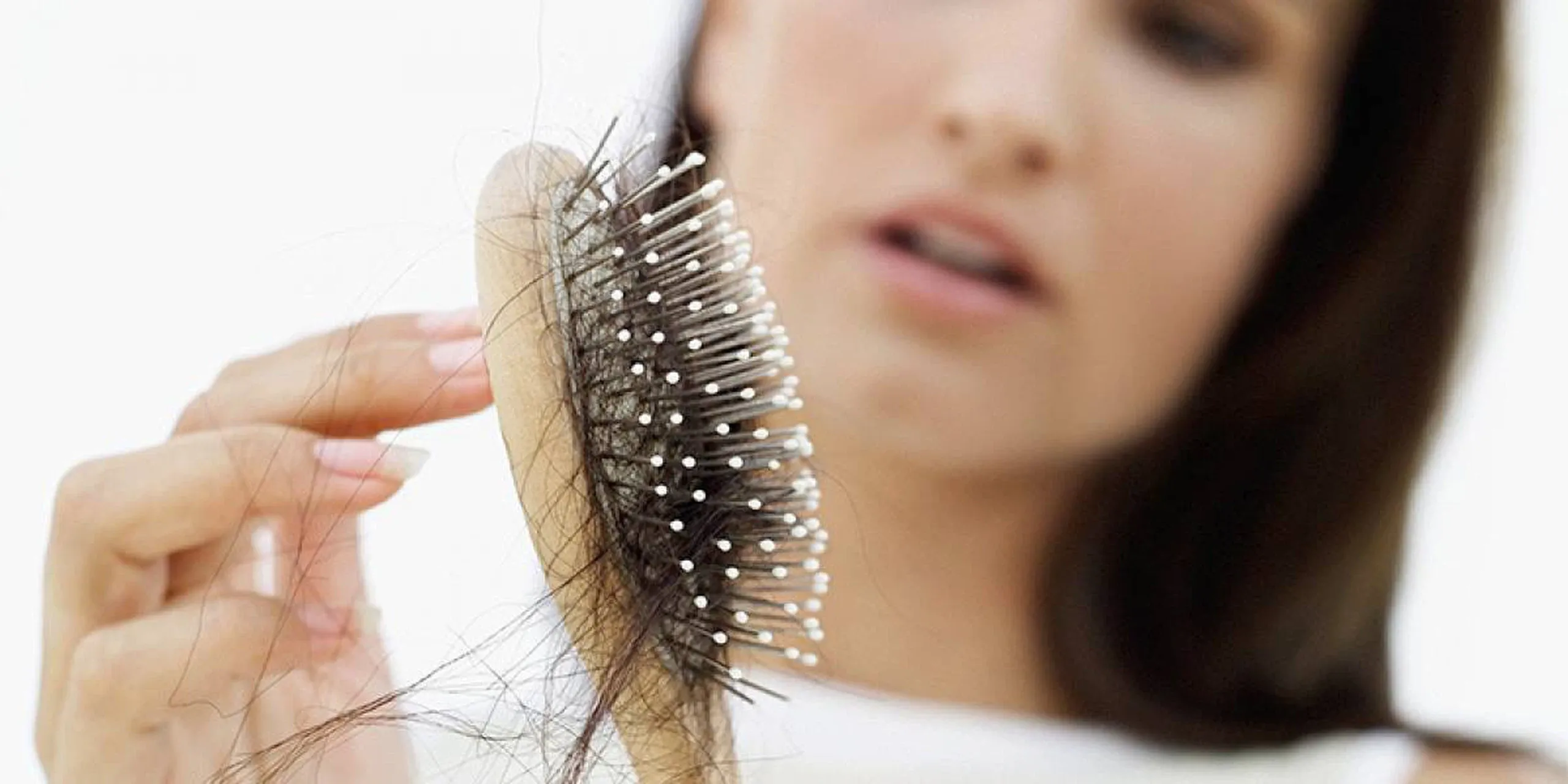 Woman noticing excessive hair loss on a hairbrush