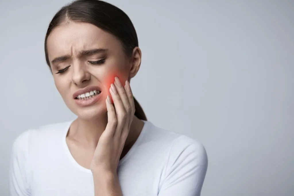 Woman experiencing acute tooth pain with cheek tenderness