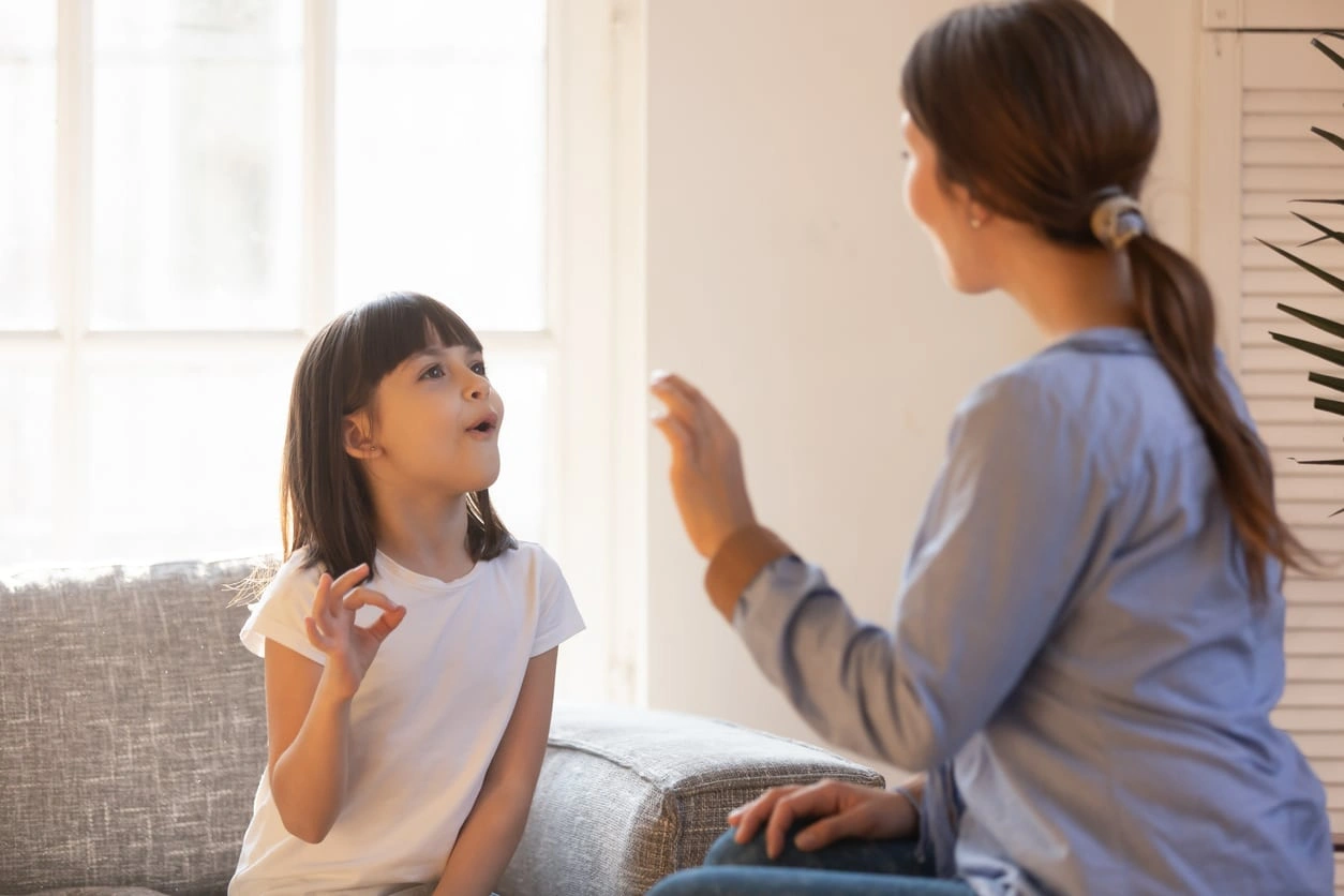 Voice Disorders A speech therapist guiding a young girl through vocal exercises during a speech therapy session for pediatric voice disorders